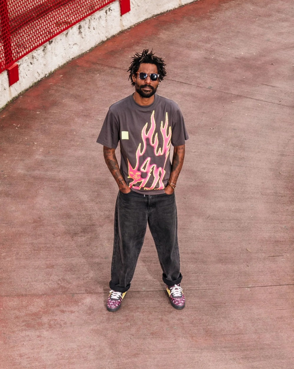 Skater in a Lakai x RIPNDIP flame cat tee, shot from above on a red court